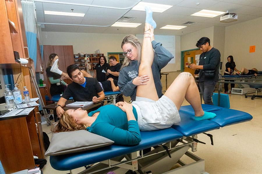 一个学生在拉另一个躺在治疗台上的学生的腿